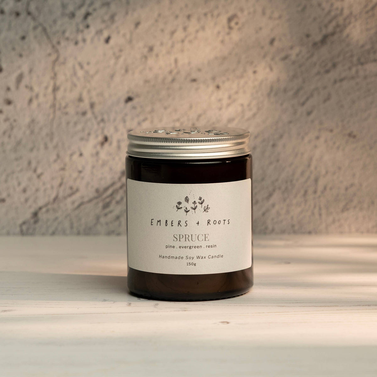 Embers & Roots Spruce Christmas Tree soy candle in an amber glass jar with silver lid