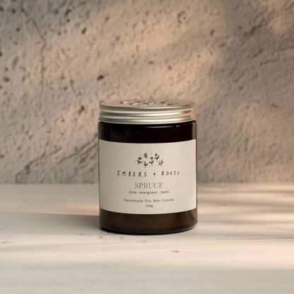 Embers & Roots Spruce Christmas Tree soy candle in an amber glass jar with silver lid
