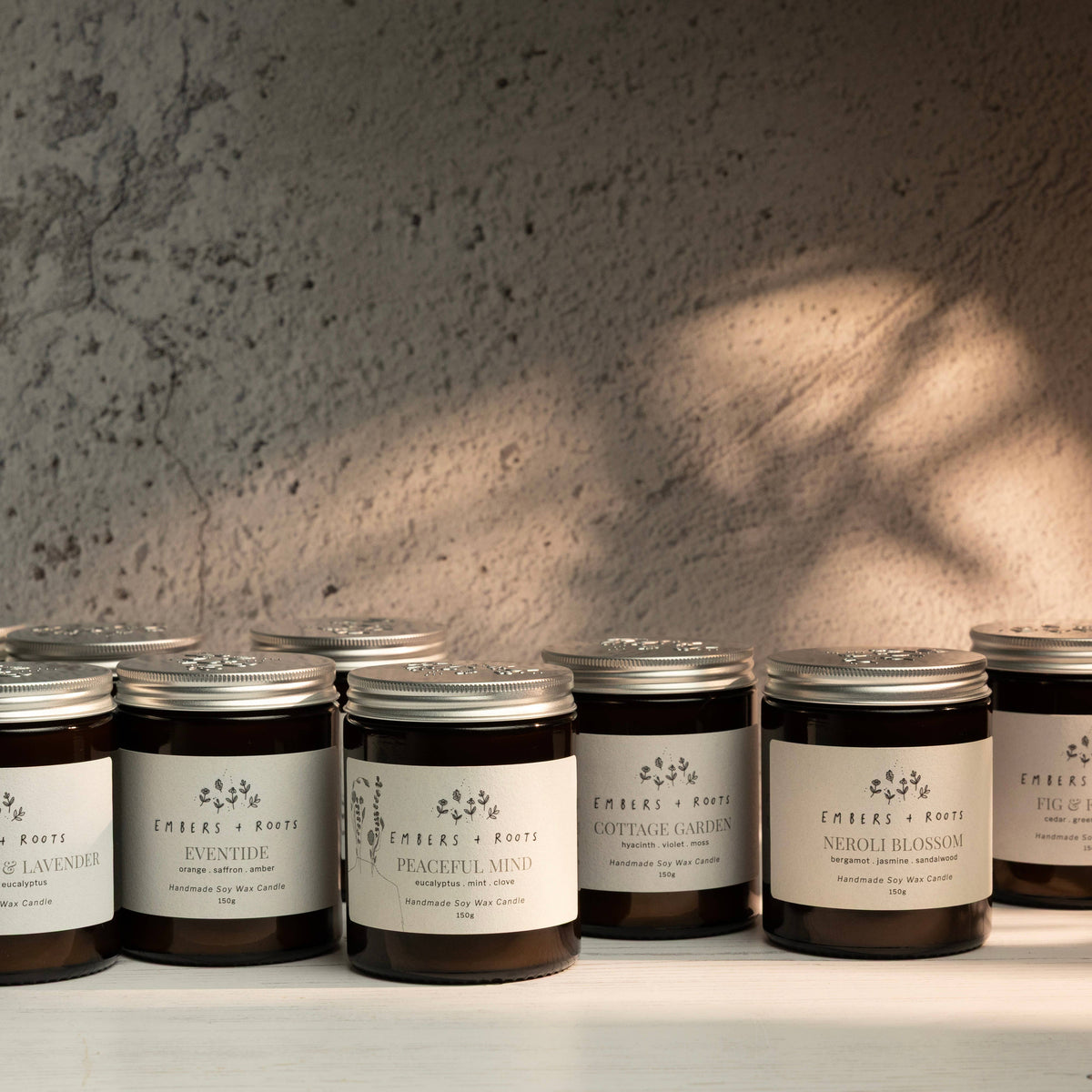 Embers & Roots soy candle jars grouped on a shelf in soft natural light