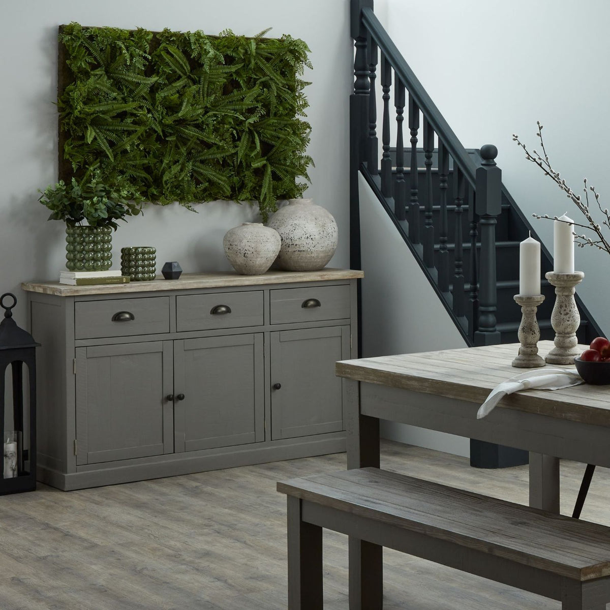 Gray sideboard with decorative items in a room with a staircase and wooden table.