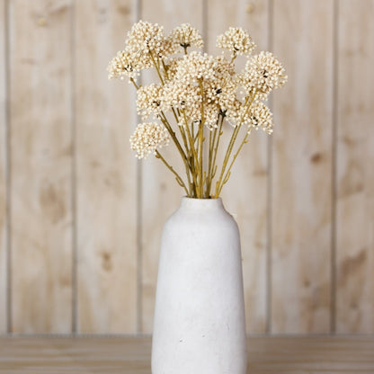 White vase with dried flowers against a wooden background
