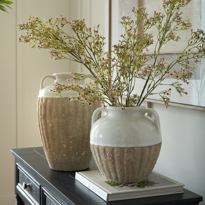 Two ceramic vases with textured design and dried flowers on a surface.