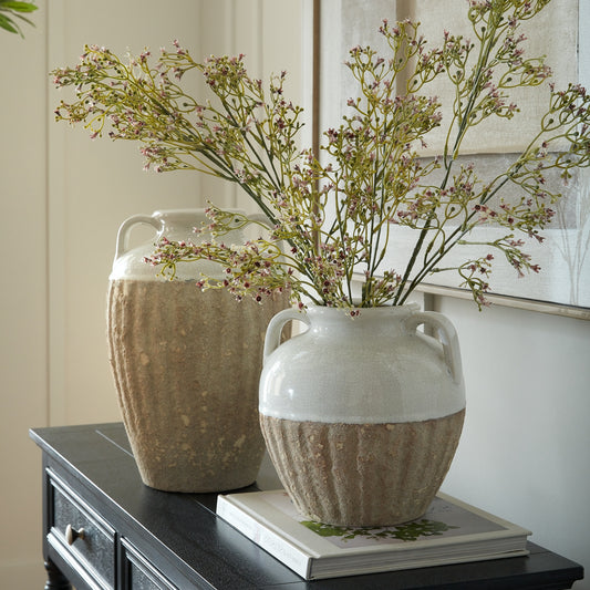 Two ceramic vases with textured design and dried flowers on a surface.