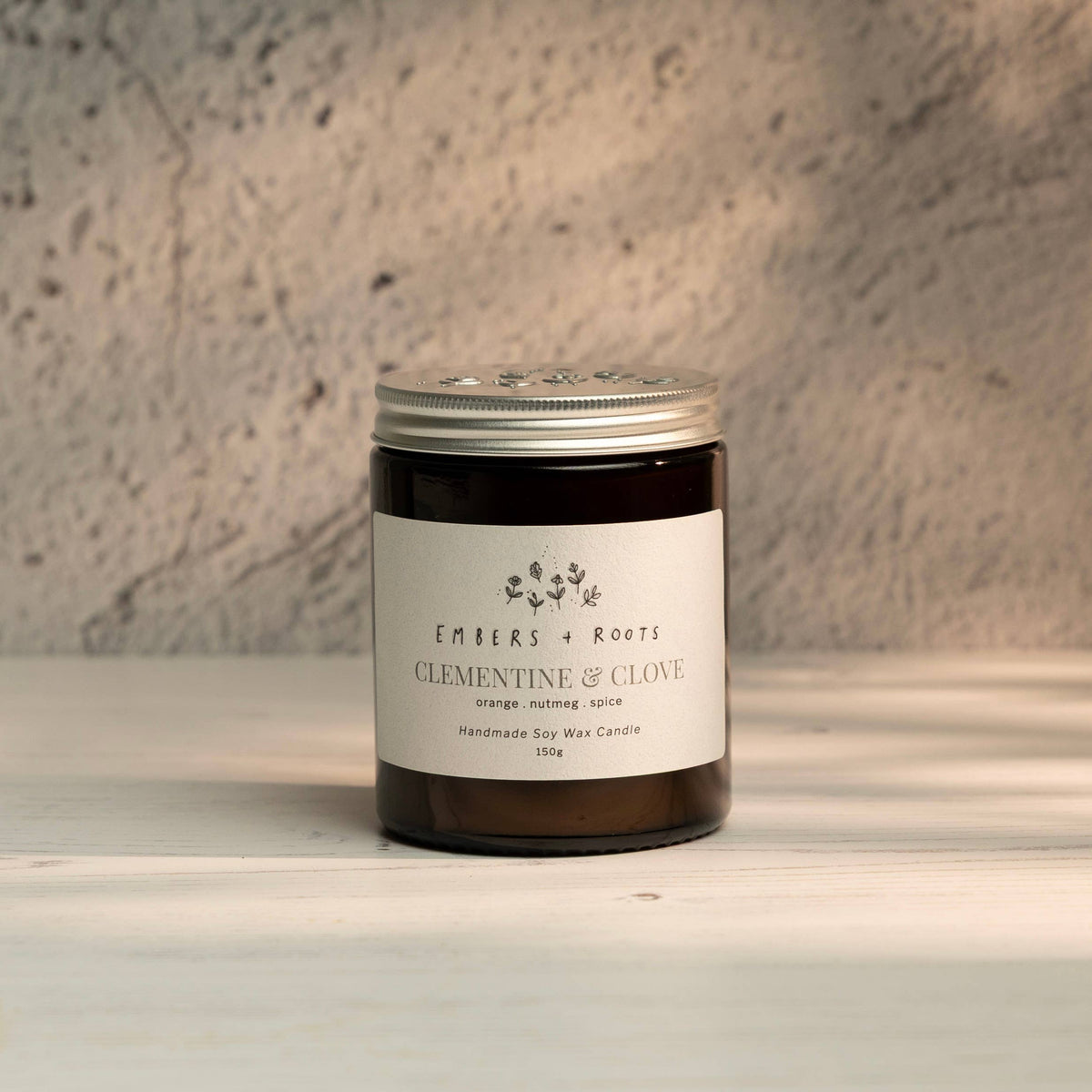 Embers & Roots Clementine & Clove Christmas soy candle in an amber glass jar