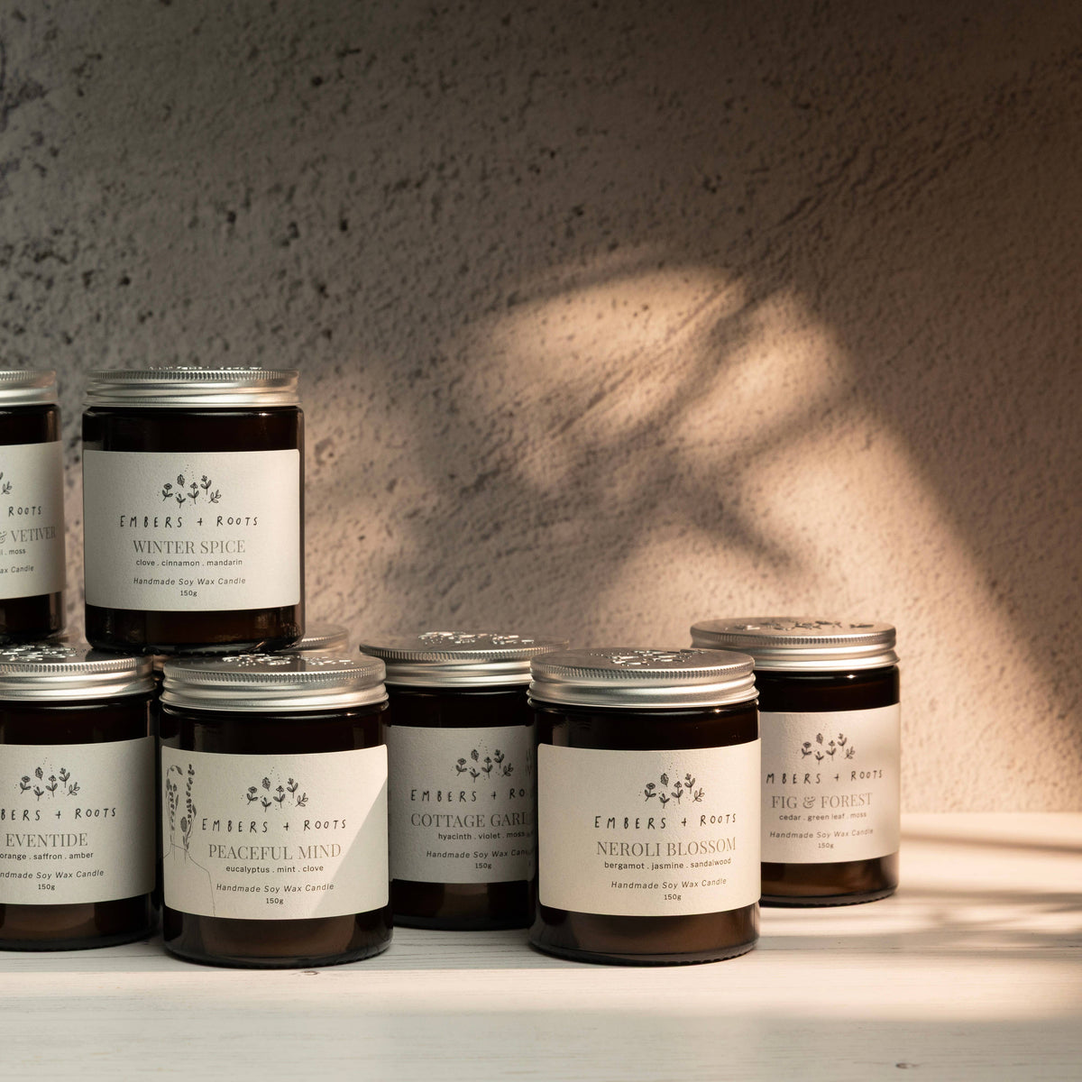 Collection of Embers & Roots soy candles displayed together in natural light