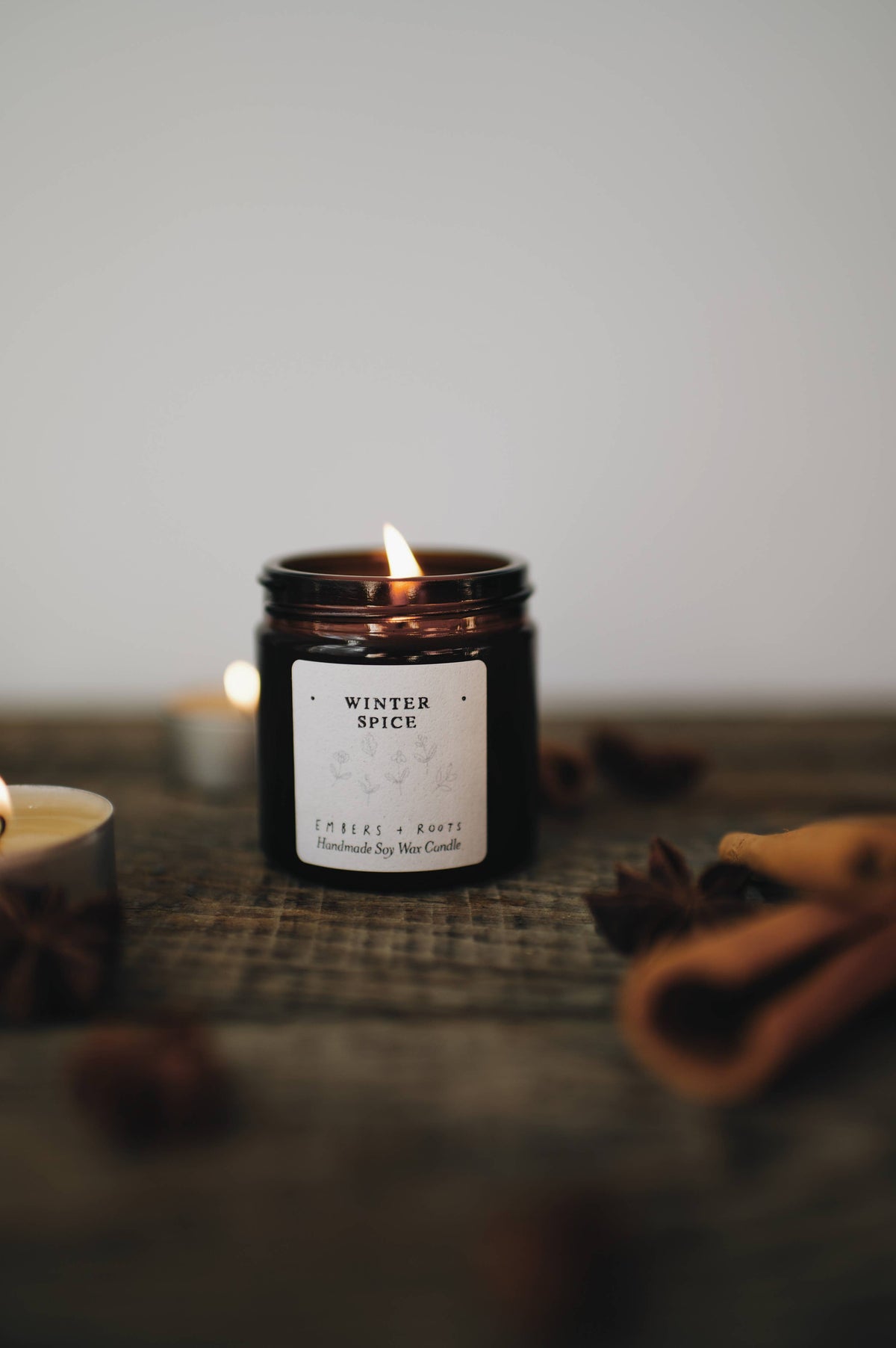 Lit Embers & Roots Winter Spice candle in an amber glass jar