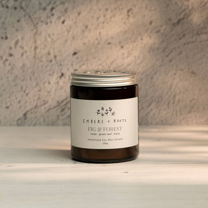 Embers & Roots Fig & Forest soy candle in an amber glass jar with silver lid