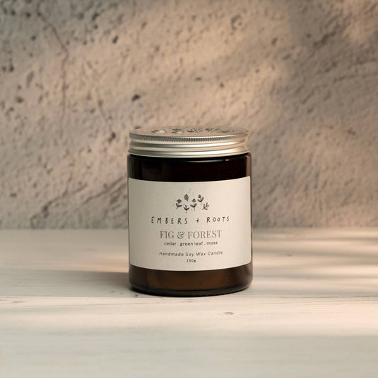 Embers & Roots Fig & Forest soy candle in an amber glass jar with silver lid