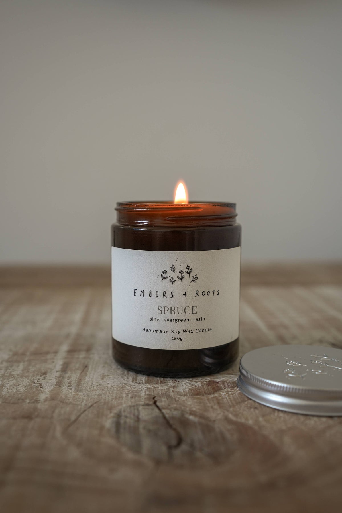 Lit Embers & Roots soy candle photographed in a home setting