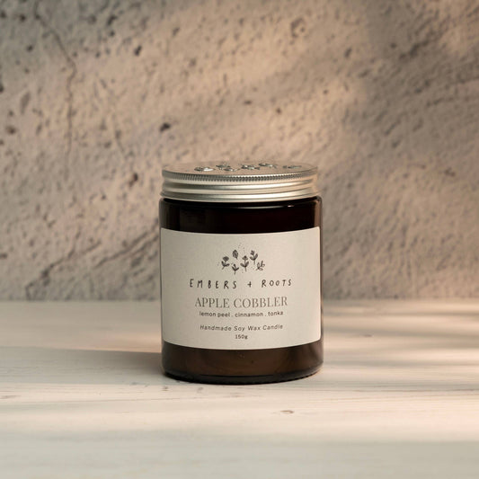 Embers & Roots Apple Cobbler soy candle in an amber glass jar with silver lid