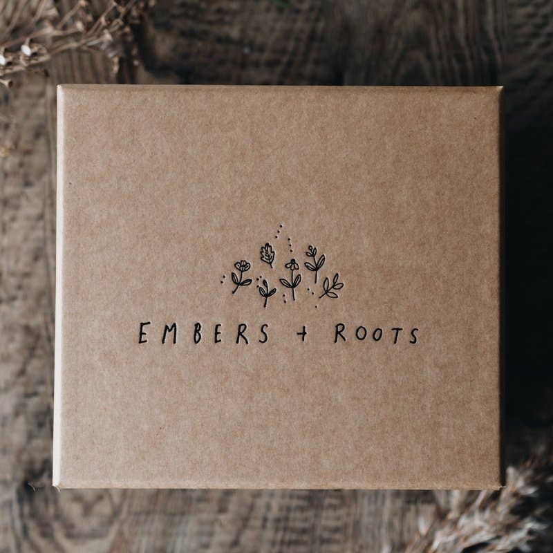 Closed kraft Embers & Roots Christmas gift box with printed floral logo